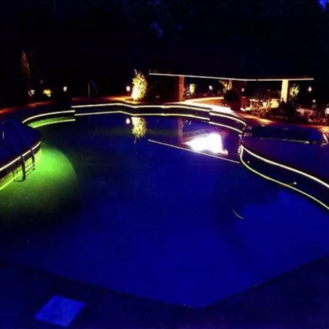 Blue and green side-glow fiber strip lighting a swimming pool edge at night