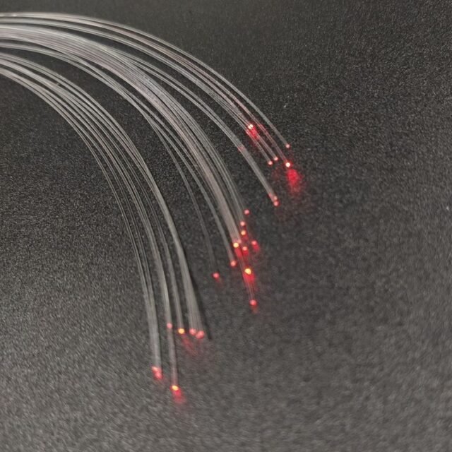 Bare DB-400 PMMA fiber strands glowing red at the ends