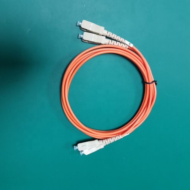 Orange duplex SC-SC multimode glass fiber patch cord coiled with beige SC connectors on green background