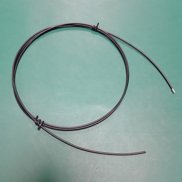 Black single-core PMMA fiber optic sensor jumper with metal ferrule probe end on green work mat