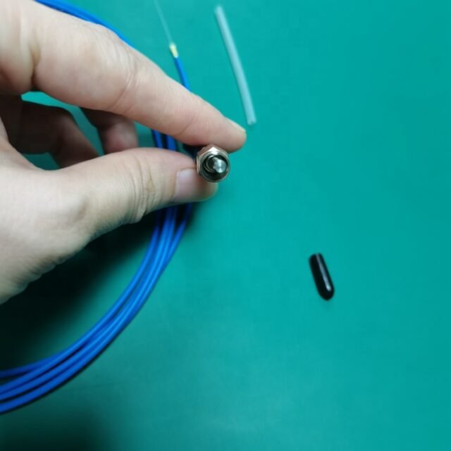 Hand holding SMA905 metal connector on blue POF pigtail