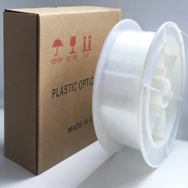Clear Toray PMMA POF on a white spool beside a printed plastic-optic shipping carton