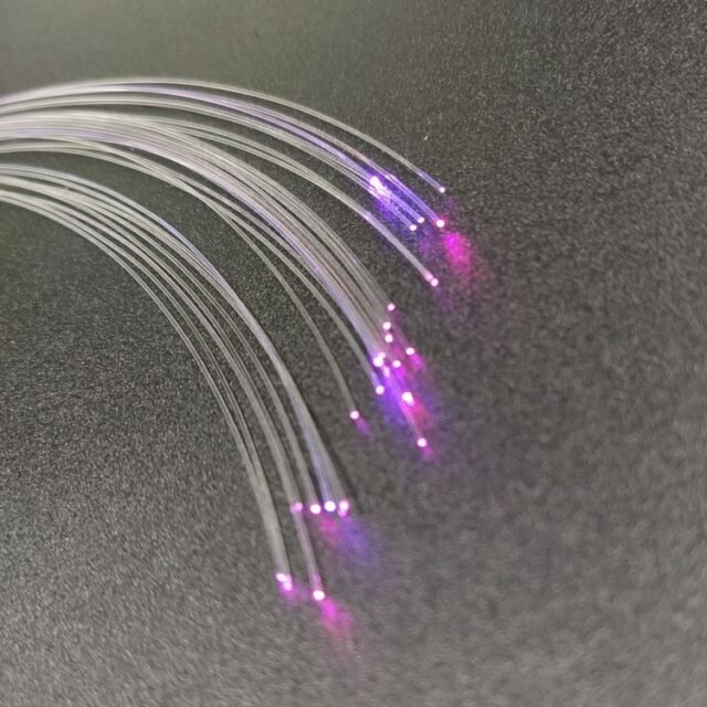 Bundle of clear PMMA fibres fanning out with purple end glow