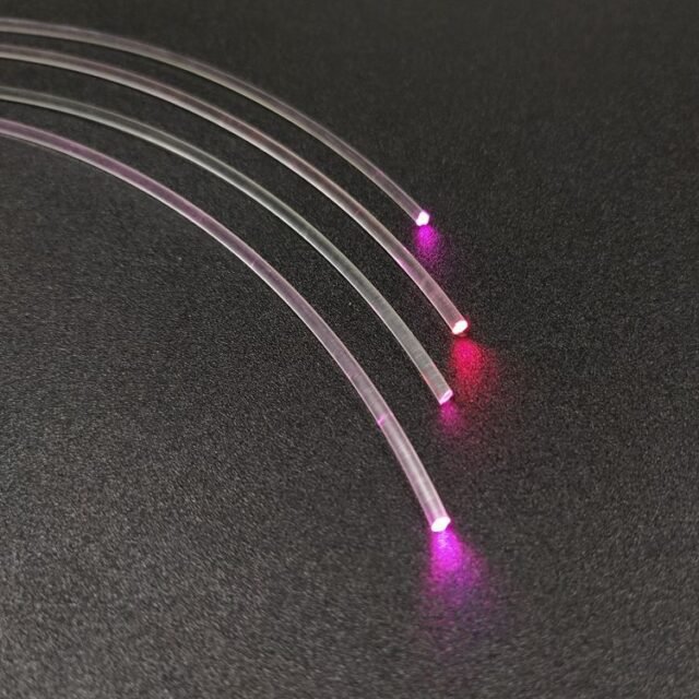 Several clear PMMA fibres of different diameters glowing red at the ends